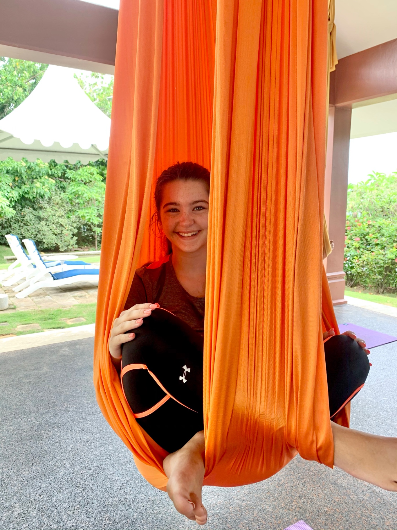 Student smiling inside an orange silk hammock