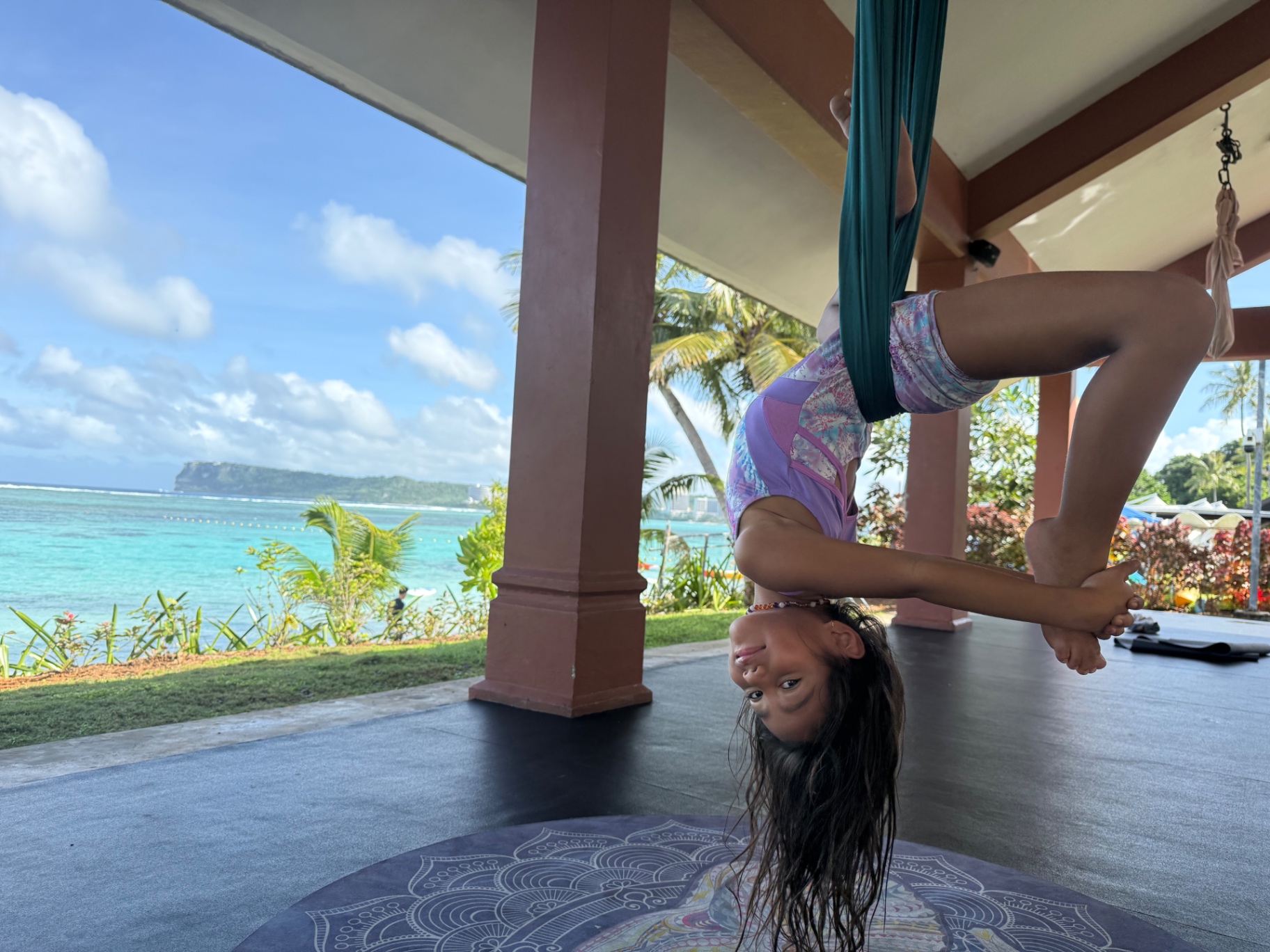 Young student smiling upside down with the Pacific behind